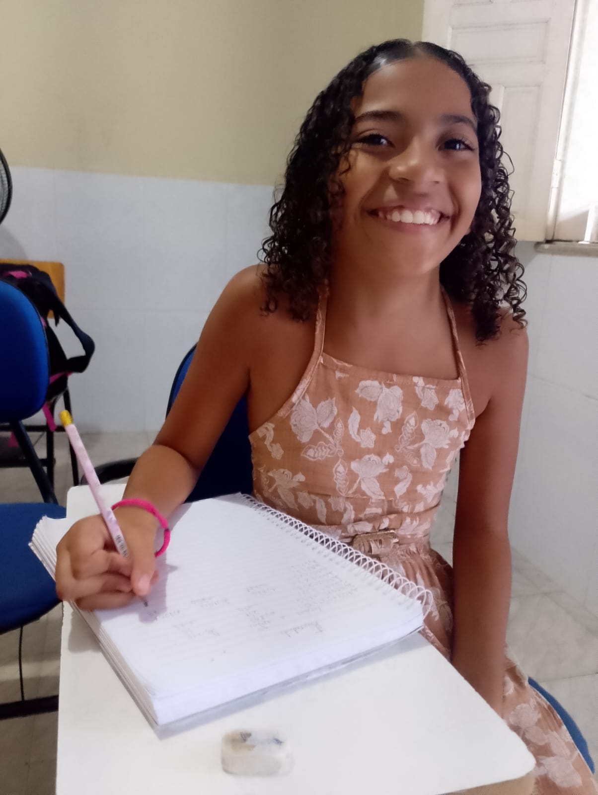 Aluna do projeto escrevendo no caderno na sala de reforço