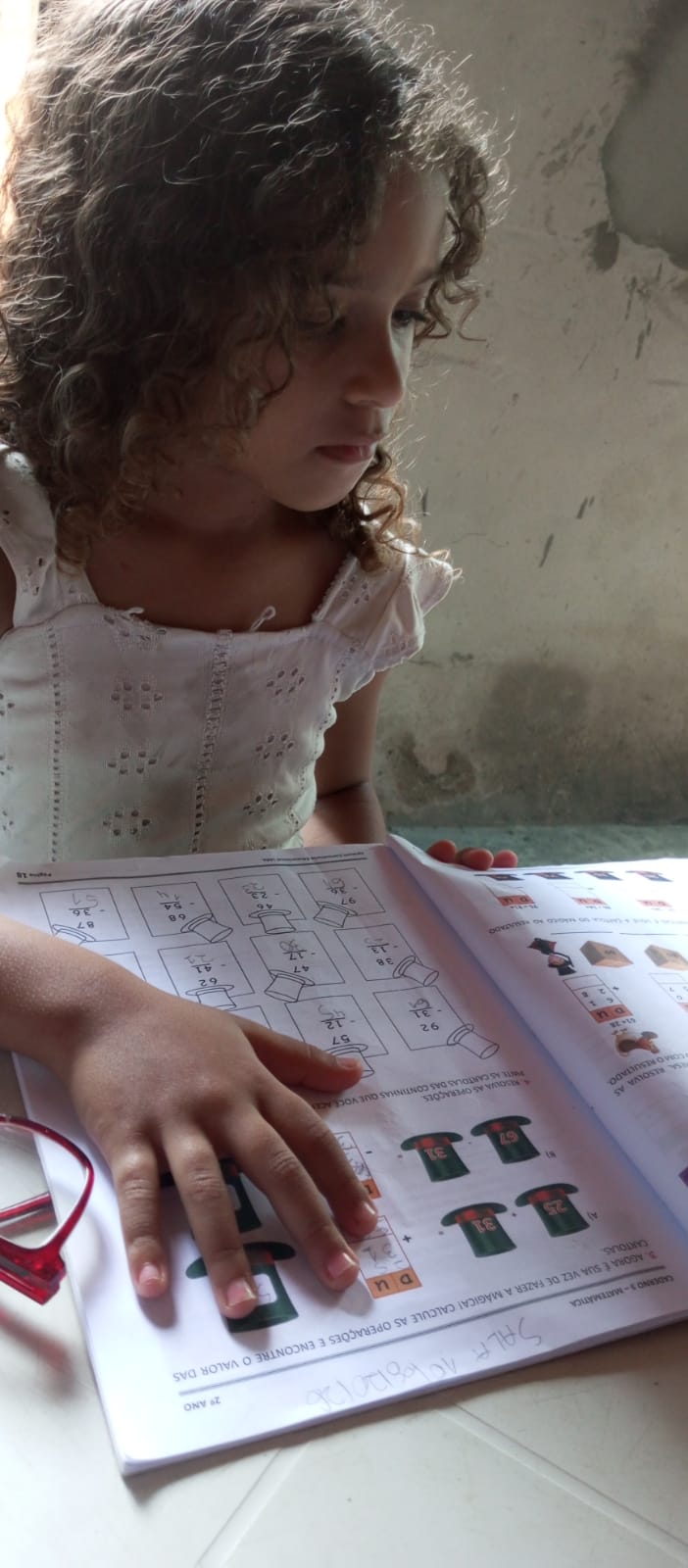 Aluna do projeto resolvendo as contas da apostila de matemática