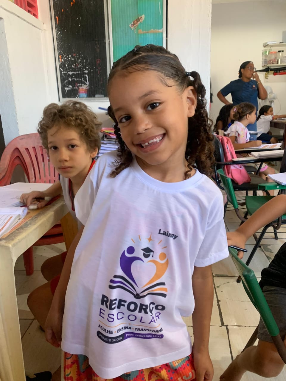 Aluna sorrindo com a camiseta do reforço escolar durante a aula