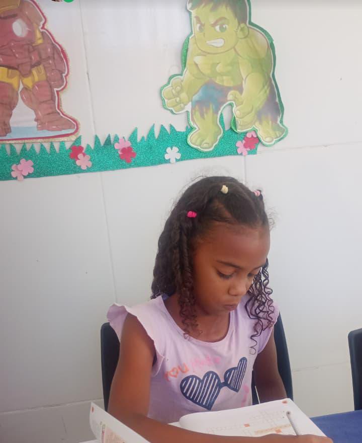 Aluna do projeto escrevendo no caderno durante a aula