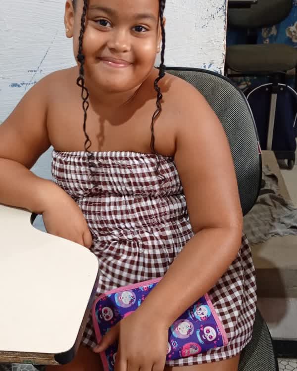 Aluna do projeto sorrindo na carteira, com o estojo na mão