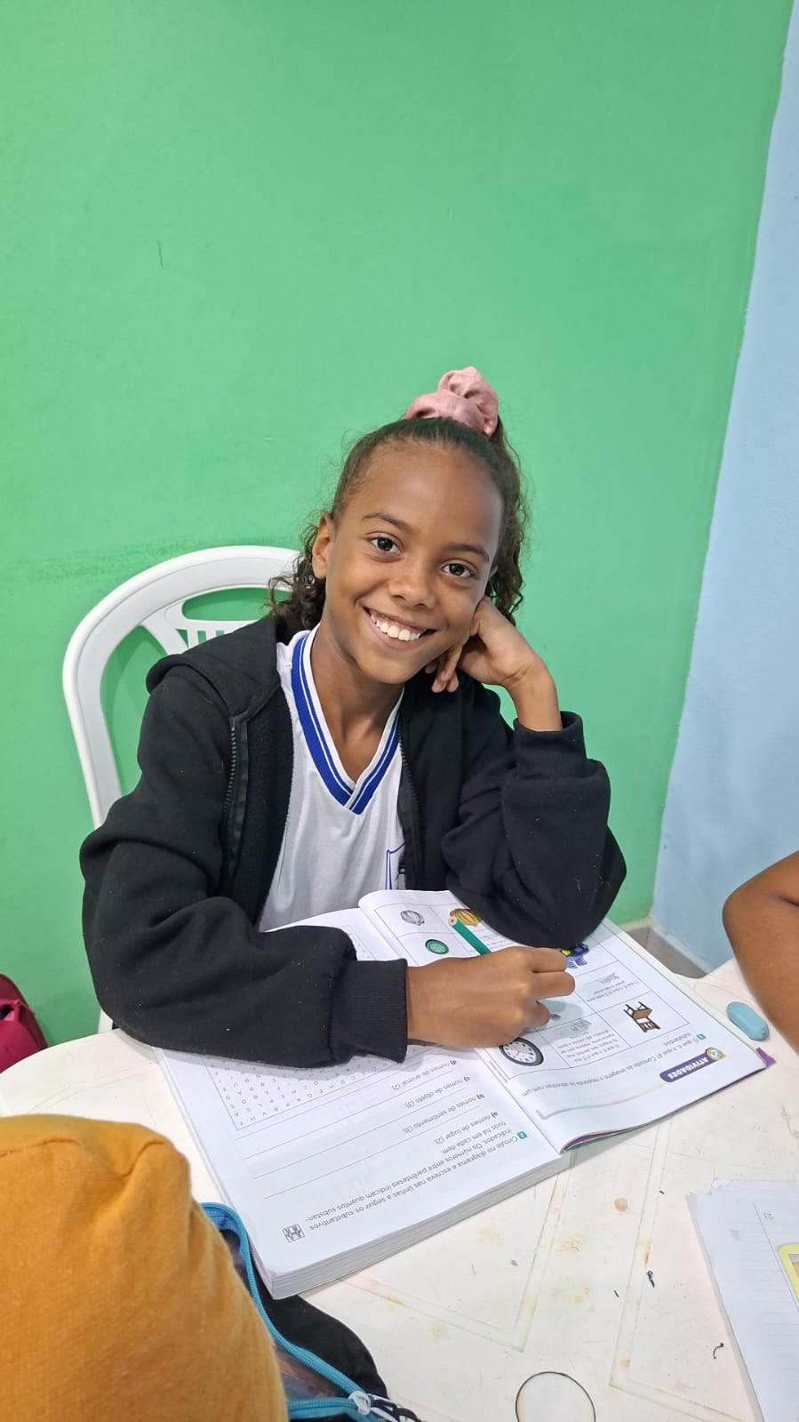 Aluna do projeto sorrindo durante a atividade no livro