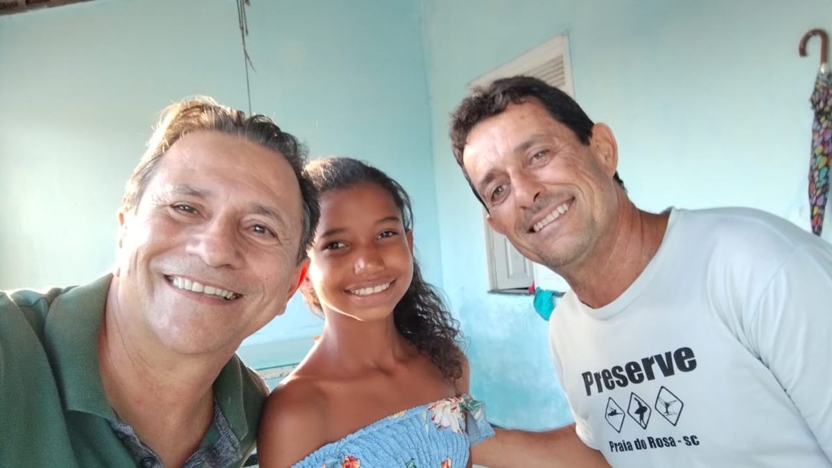Aluna do projeto sorrindo durante a visita da equipe do reforço à casa dela