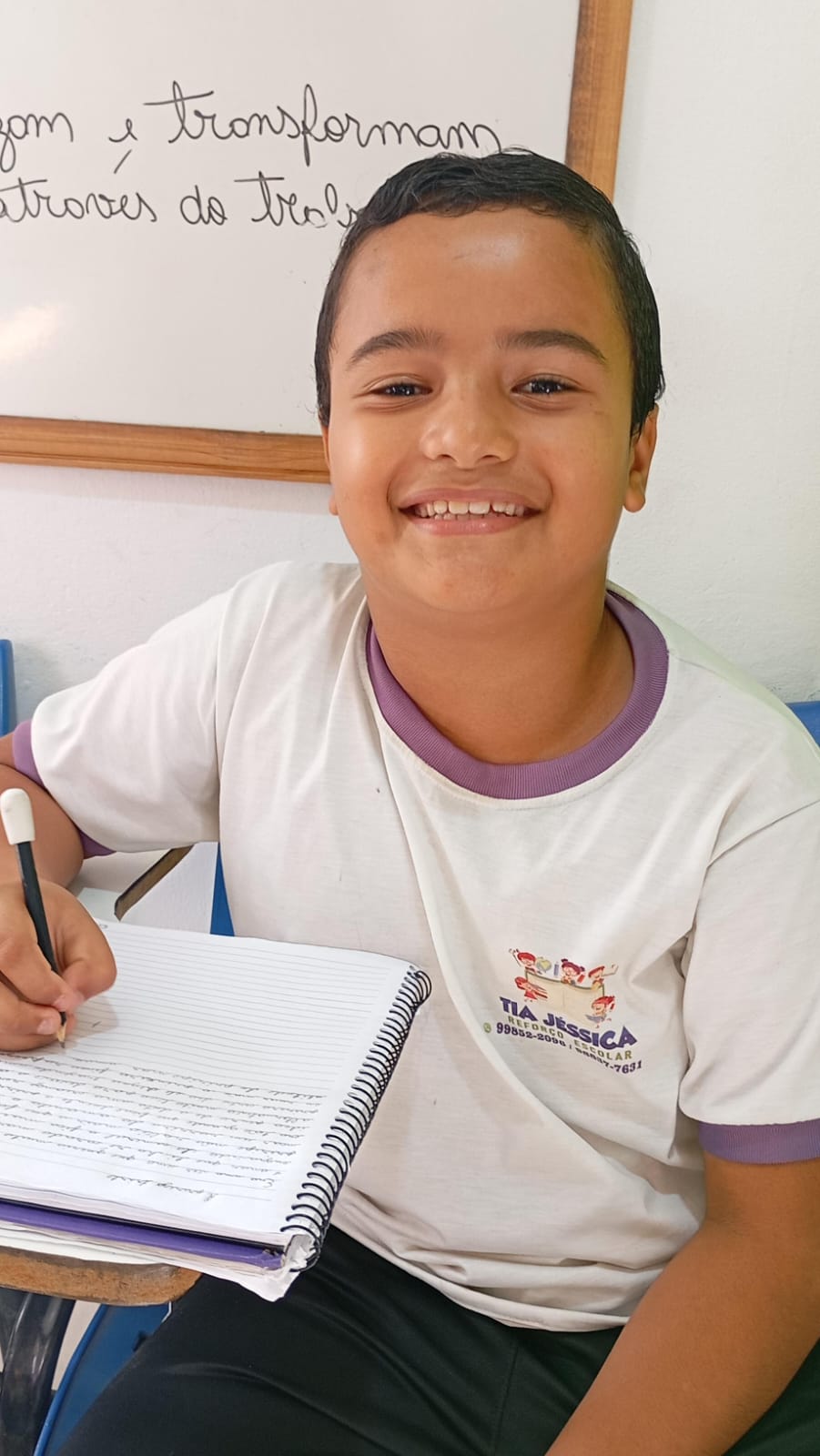 Aluno do projeto sorrindo com o caderno aberto