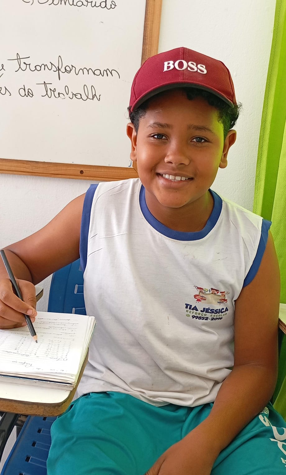 Aluno do projeto de boné escrevendo no caderno durante o reforço