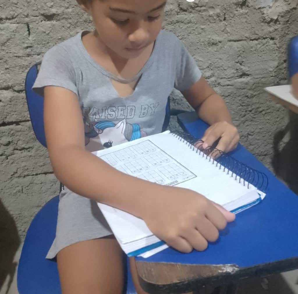 Aluna do projeto conferindo a atividade no caderno