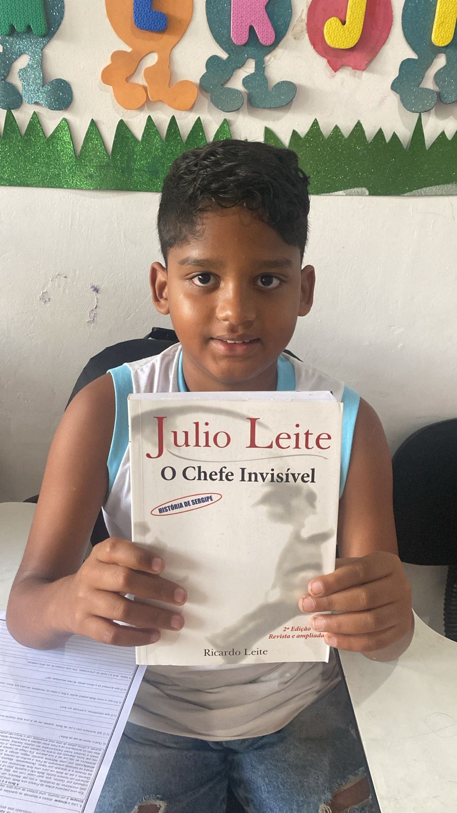 Aluno do projeto segurando um livro de história de Sergipe recebido no reforço